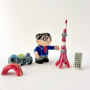 Small collection of sculptures: a business man with glasses, the Tokyo tower, small buildings and a red bridge.
