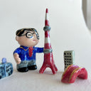 Small collection of sculptures: a business man with glasses, the Tokyo tower, small buildings and a red bridge.