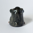 Back view of a ceramic hamster, dark gray in color.