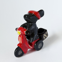 Ceramic sculpture of a black bunny with a red visor, riding a red motorized scooter with a basket on the back.
