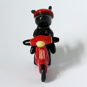 Ceramic sculpture of a black bunny with a red visor, riding a red motorized scooter with a basket on the back.