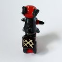 Ceramic sculpture of a black bunny with a red visor, riding a red motorized scooter with a basket on the back.