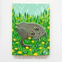 Painting of a gray cat, smiling and rolling around in grass with yellow dandelions.