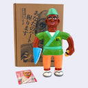 Soft vinyl figure of a tan sushi chef, holding a sushi in one hand and with a knife as his other hand.