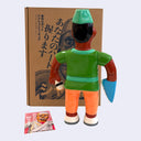 Soft vinyl figure of a tan sushi chef, holding a sushi in one hand and with a knife as his other hand.