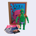 Green soft vinyl figurine of a nude, muscular Japanese man with scars all over his body. He holds a decapitated head in its hand.