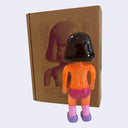Vinyl toy figure of a topless woman with glittery orange skin and pink underwear.