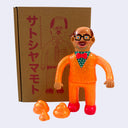 Toy figure of a man in an orange suit with a box in the background
