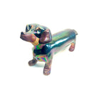 An iridescent dachshund-shaped sculpture with a metallic, rainbow-like finish on a plain white background.