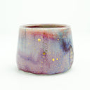 Glossy ceramic cup with a deep reddish purple to light blue gradient coloring with gold sparkles on it. 