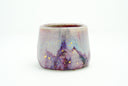 Glossy ceramic cup with a deep reddish purple to light blue gradient coloring with gold sparkles on it. 