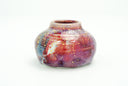 Glossy ceramic vase with a small opening and  a deep reddish purple to light blue gradient coloring with gold sparkles on it. 