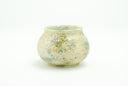 Small ceramic pot with a cream colored and light green glossy exterior with many small divets like the surface of a moon.