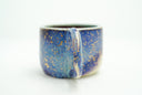 Glossy ceramic handle mug with a dark blue to light blue gradient coloring with gold sparkles on it. 