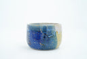 Short ceramic bowl with a blue multicolor glaze and golden splatters.