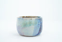 Short ceramic bowl with a blue multicolor glaze and golden splatters.