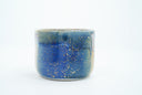 Short ceramic bowl with a blue multicolor glaze and golden splatters.
