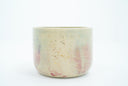 Short ceramic bowl with a light green and light purple multicolor glaze and golden splatters.