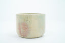 Short ceramic bowl with a light green and light purple multicolor glaze and golden splatters.