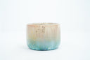 Small ceramic cup with a gradient of light brown to blue and gold speckles.