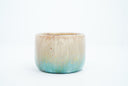 Small ceramic cup with a gradient of light brown to blue and gold speckles.