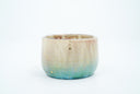 Small ceramic mug with large, thin handle and with a gradient of light brown to blue and gold speckles.