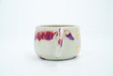 Ceramic cup with a thin handle, off white with subtle red splatter coloring. A gold dragon is painted onto the front of the mug.