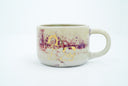 Small ceramic mug, off white with reddish purple splotches and a gold line art painting of a flower and a dog.