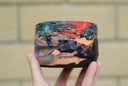 Ceramic pot with many colors and shining elements, looking like an abstract desert landscape.
