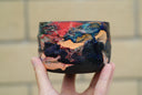 Ceramic pot with many colors and shining elements, looking like an abstract desert landscape.