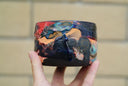 Ceramic pot with many colors and shining elements, looking like an abstract desert landscape.