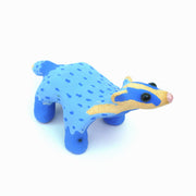 Sculpture of a blue badger, with cartoon coloring and features such as a very skinny neck, small head and large round black eyes.