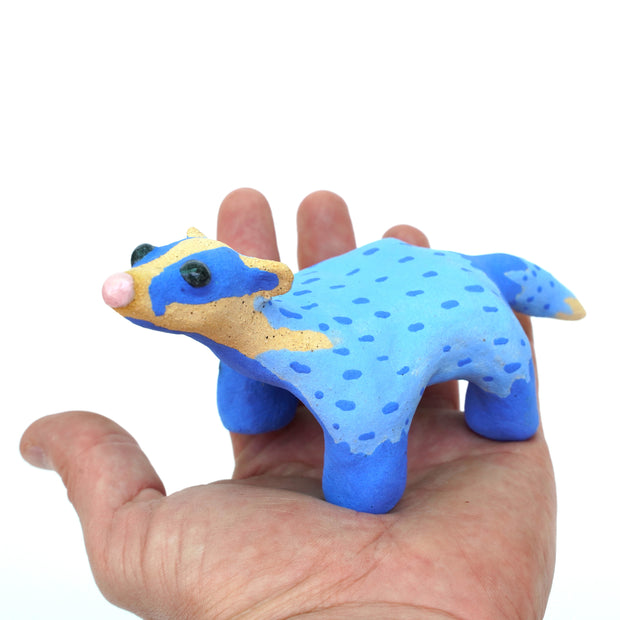 Sculpture of a blue badger, with cartoon coloring and features such as a very skinny neck, small head and large round black eyes.