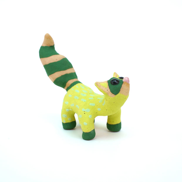Sculpture of a green racoon with a large fluffy tail and cartoon style features, such as an upturned head and large black eyes.
