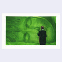 Person standing in front of a large green screen, which shows a person sleeping.