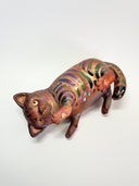 Ceramic cat figurine, reddish brown in color with chromatic stripes. It lays on its back in a playful position.