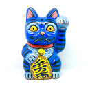 A hand-painted blue maneki-neko lucky cat figurine with black stripes, yellow eyes, pink inner ears, and a red collar, holding a yellow sign with black kanji characters, set against a plain white background.