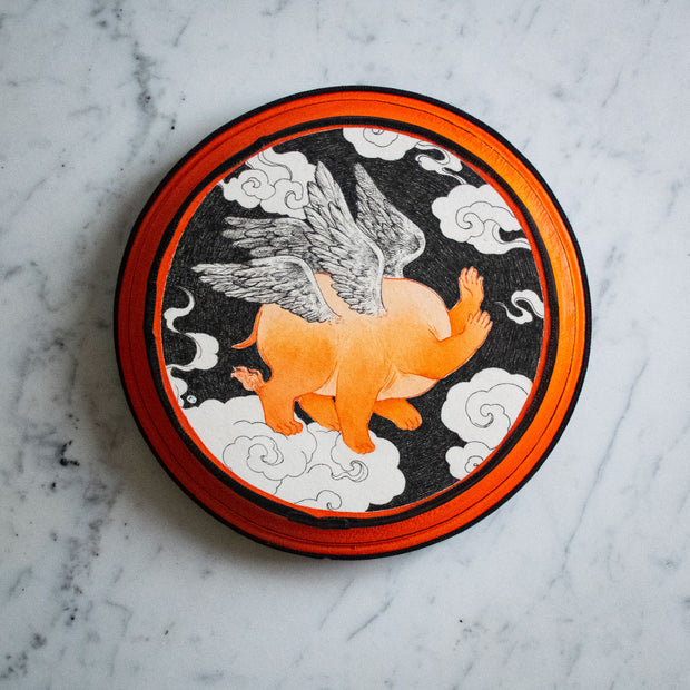 Black, white and orange illustration on a round orange and black panel. A flying creature with the body of a pig and head stands on a cloud with 6 legs and 2 pairs of wings.