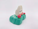 Small wooden sculpture of a white Chibi Totoro sitting on a green base with tiny mushroom around.