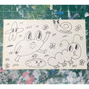 Ink doodles on an index card of a frog, snail and caterpillar all with human-like facial expressions.