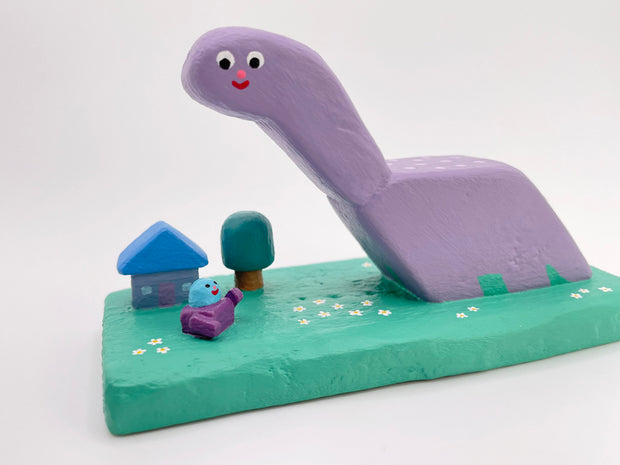 Purple dinosaur-like creature with a small house and tree on a green base against a white background