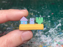 Small sculpture with a house, a purple frog and a cactus.