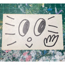 Ink drawing of a cartoon face on an index card.
