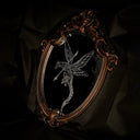 An ornate oval wall mirror with a distressed bronze frame, featuring a white-line engraved illustration of a dragon with a spear shot through it.