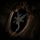 An ornate oval wall mirror with a distressed bronze frame, featuring a white-line engraved illustration of a dragon with a spear shot through it.