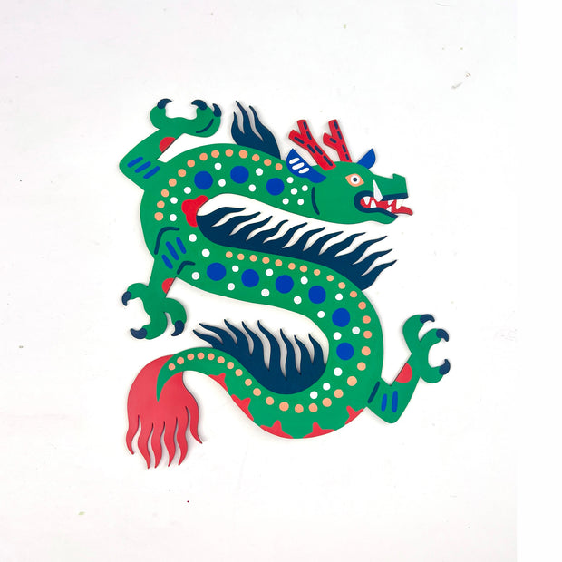 Die cut wooden painted sculpture of a green dragon with patterning and bright coloring akin to folk art, with many polka dots and a wild mane and tail.