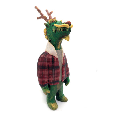 Sculpture of a green dragon with wooden antlers and yellow/gold color accents. It stands on 2 legs like a human and wears a red sherpa flannel jacket.