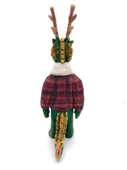 Sculpture of a green dragon with wooden antlers and yellow/gold color accents. It stands on 2 legs like a human and wears a red sherpa flannel jacket.