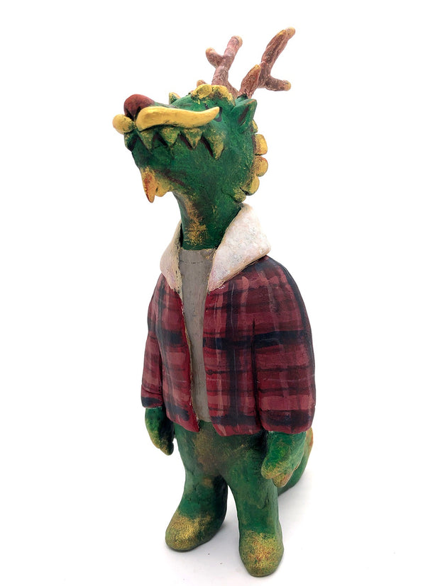 Sculpture of a green dragon with wooden antlers and yellow/gold color accents. It stands on 2 legs like a human and wears a red sherpa flannel jacket.