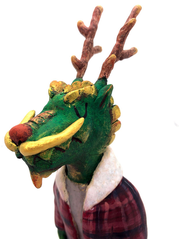 Sculpture of a green dragon with wooden antlers and yellow/gold color accents. It stands on 2 legs like a human and wears a red sherpa flannel jacket.